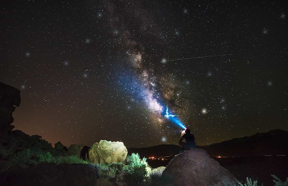 A person stargazing at the night sky while camping in the desert